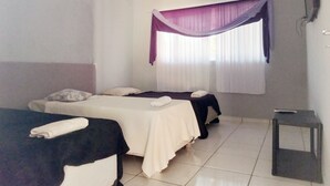 A room with two beds, a ceiling fan, a window with curtains, and a television on the wall.