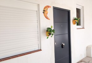 A closed white roller door with a black door, a small window with a potted plant, and a decorative crescent moon on the wall. - Hidden gem! 1 bedroom flat, mins walk to La Cala (Mijas)