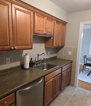 A kitchen with wooden cabinets, a stainless steel sink, and a dishwasher. - Delightful 2-bedroom apartment with balcony in Sterling Heights (Sterling Heights)