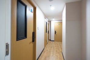 A hallway with wooden doors, a light-colored floor, and a ceiling with recessed lighting. - Xiaobai Youth Hotel (Beijing)