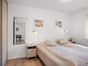 A bedroom with a bed, bedside tables, a mirror, and wall art. - "Ineke" - 200m from the sea by Interhome (Lemvig)