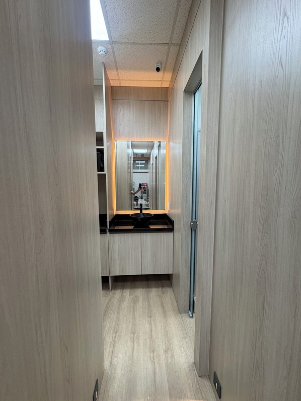 A narrow hallway with wooden walls and a central counter with a sink.