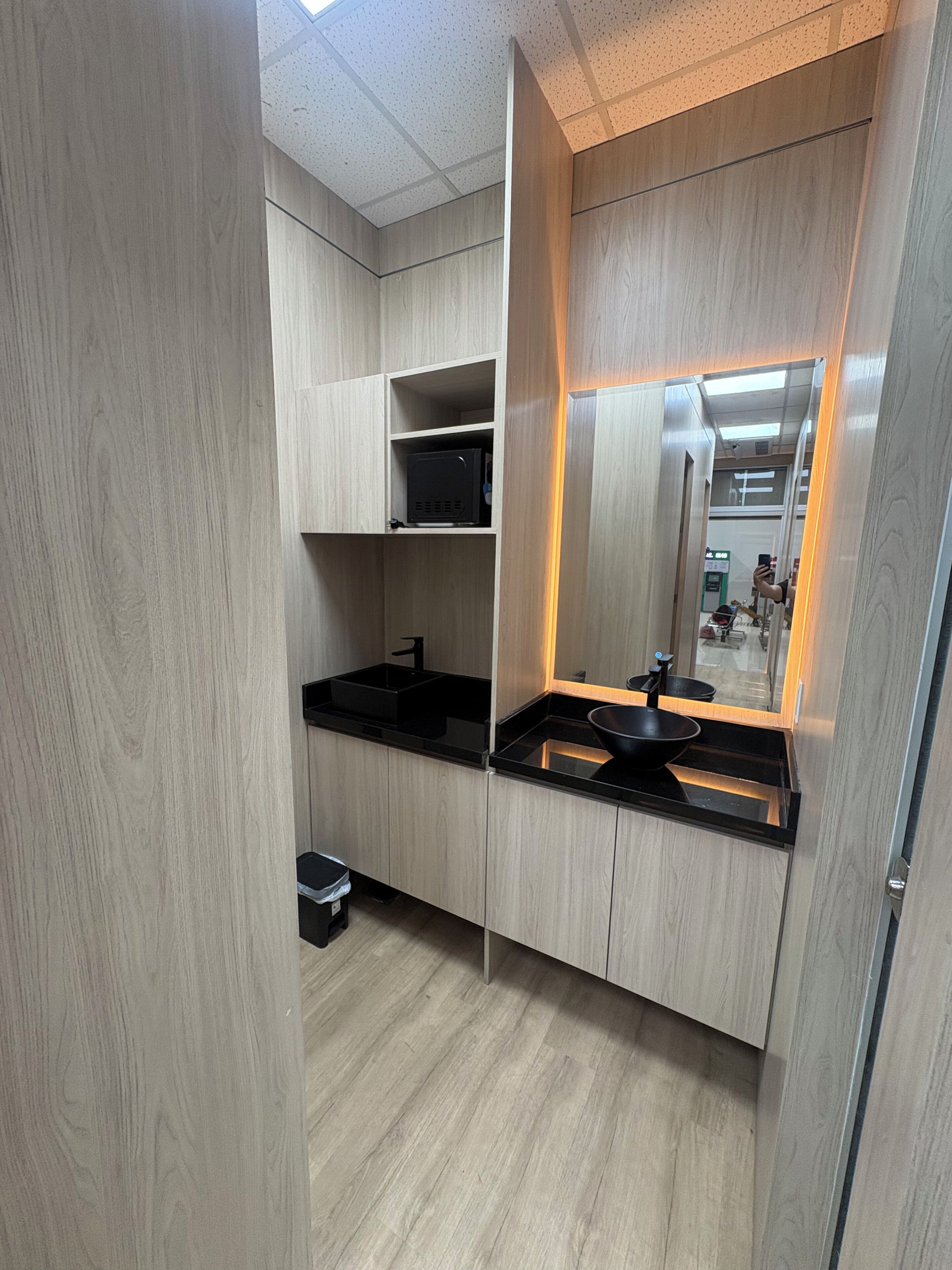 Una cocina moderna con armarios de madera, encimeras negras y un lavamanos integrado.