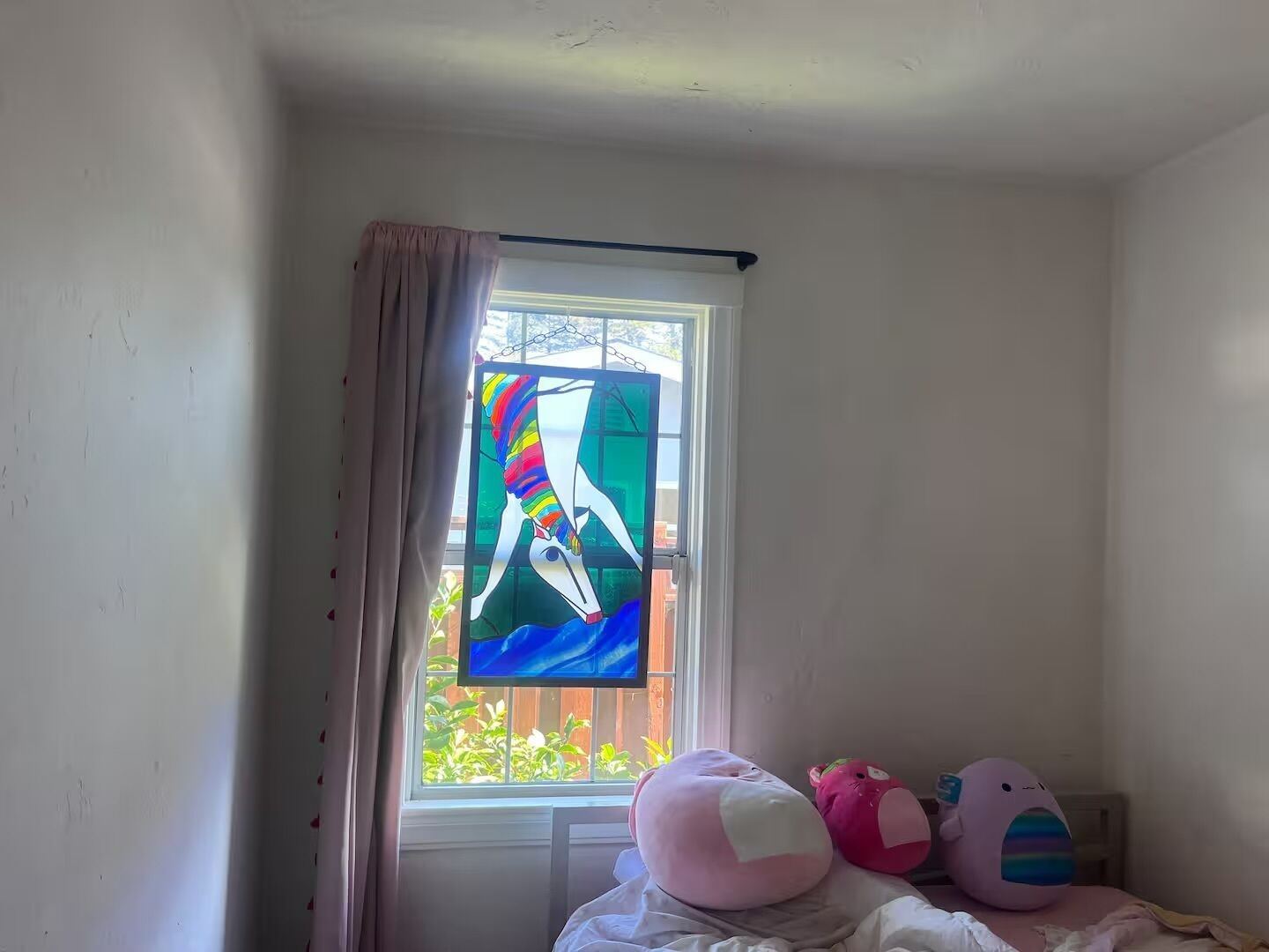 Un dormitorio con ventana, cama y un peluche.