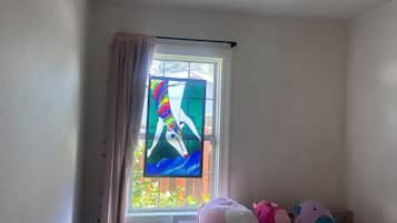 Un dormitorio con ventana, cama y un peluche.