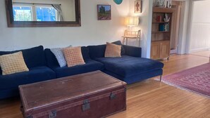 A living room with a dark blue sofa, a wooden coffee table, and a large mirror on the wall. - Perfect 3 bedroom house with AC in awesome Petaluma neighborhood near downtown (Petaluma)