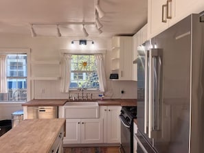 A kitchen with white cabinets, a stainless steel refrigerator, a stove, and a window with a sun design. - Perfect 3 bedroom house with AC in awesome Petaluma neighborhood near downtown (Petaluma)