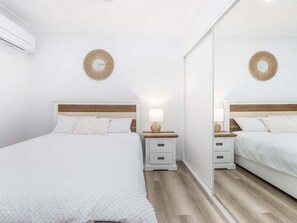 Une chambre à coucher comprenant un lit, deux tables de chevet, un miroir et un élément de décoration circulaire fixé au mur.