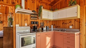 Cocina con paredes de madera, estufa, armarios y un lavamanos.