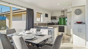Cocina moderna con comedor, un reloj en la pared y vistas al exterior.