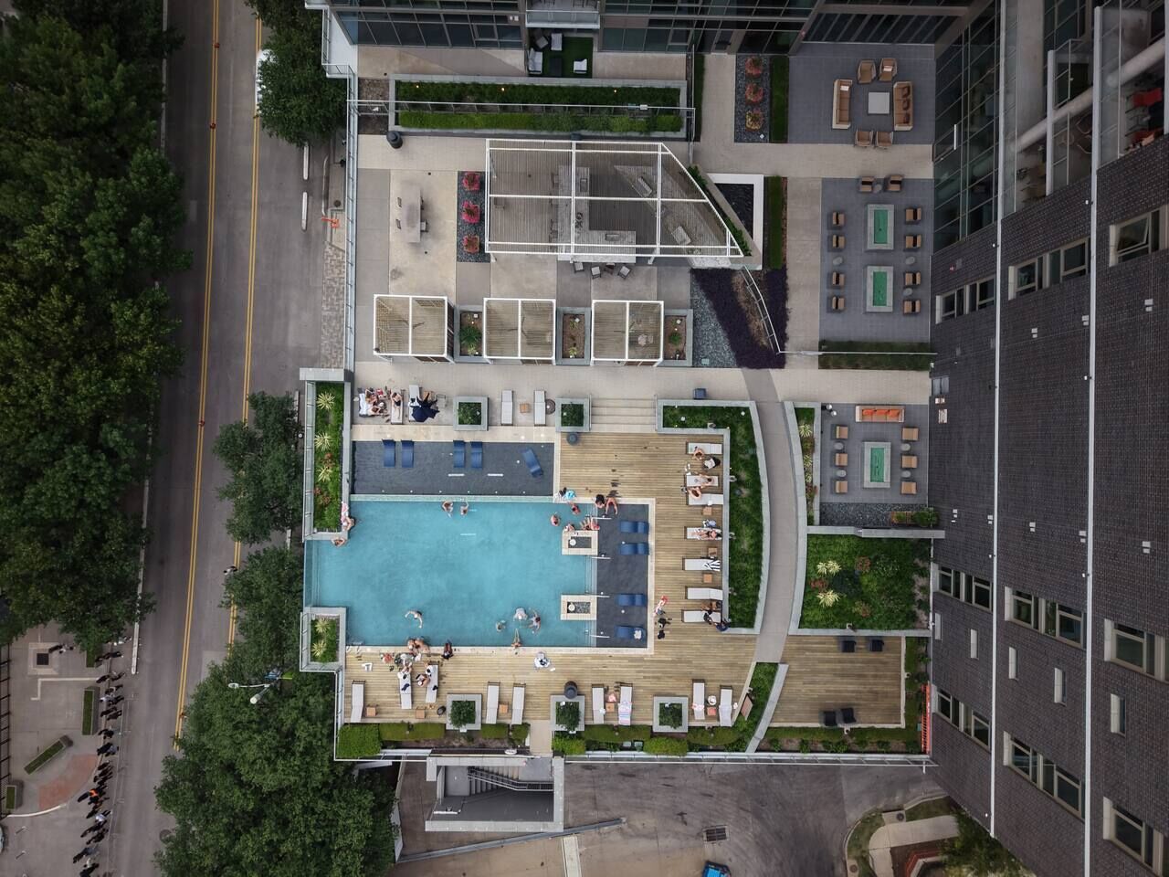 An aerial view of a rooftop pool area with multiple seating zones and a central swimming pool.
