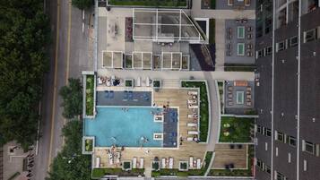 An aerial view of a rooftop pool area with multiple seating zones and a central swimming pool.