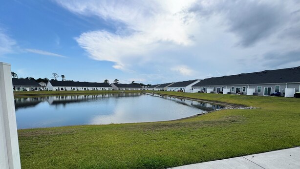Um bairro residencial com um grande lago, casas com arquitetura uniforme e céu claro.