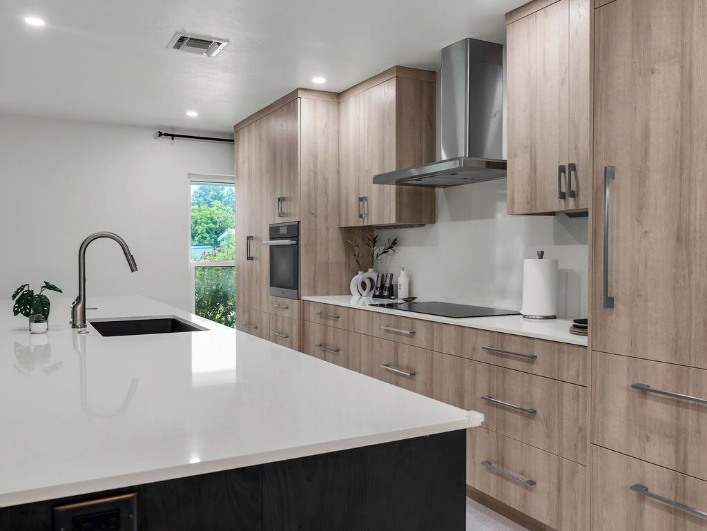 A modern kitchen with wooden cabinets, a stainless steel range hood, and a large island with a sink.