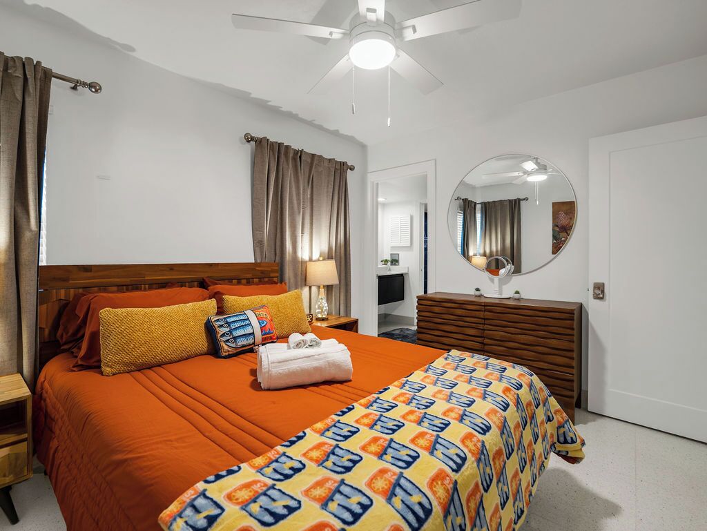 Un dormitorio con cama, cómoda, espejo y ventilador de techo.