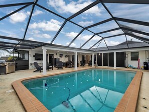 An indoor swimming pool with a glass ceiling, surrounded by lounge chairs and a barbecue grill. - Waterfront retreat with heated pool and private dock! (Port Charlotte)