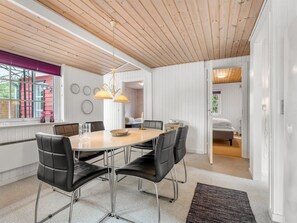 A modern dining area with a round table, black chairs, and pendant lighting.