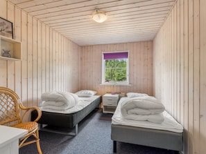 Una habitación pequeña y acogedora con dos camas, un escritorio y una silla.