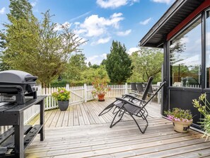 A wooden deck with outdoor furniture, a grill, and potted plants. - "Aiske" - 700m from the sea by Interhome (Dannemare)