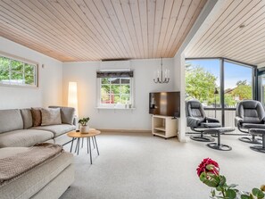 A modern living room with a sofa, a small table with a plant, a TV, and a seating area with chairs. - "Aiske" - 700m from the sea by Interhome (Dannemare)