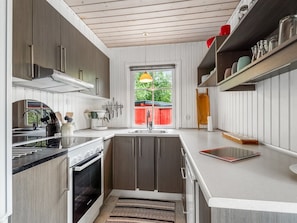 A modern kitchen with a built-in oven, a sink, and a window with a view of the outdoors. - "Aiske" - 700m from the sea by Interhome (Dannemare)
