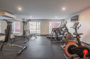 A gym with various exercise equipment, large windows, and a flat-screen TV on the wall. - Spacious 3 1/2-bedroom condo in Montreal (Montréal)