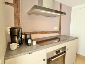 A modern kitchen with a coffee maker, mug, and a built-in oven. - Renovated, intimate rural village house (Palenge)