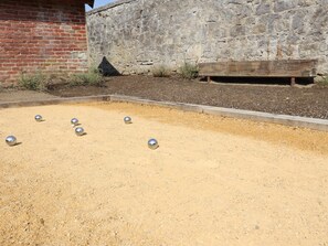 A courtyard with a billiards setup, a stone wall, and a wooden bench. - Renovated, intimate rural village house (Palenge)