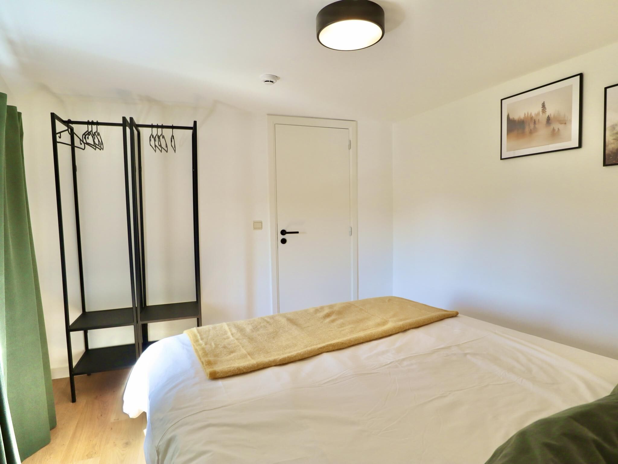 Ein Schlafzimmer mit einem Bett, einem Kleiderschrank, einer Tür und zwei gerahmten Bildern an der Wand.