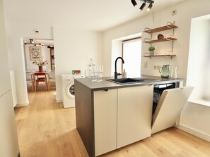 Eine moderne Küche mit integriertem Geschirrspüler, Spüle und Essbereich inklusive Tisch und Stühlen.