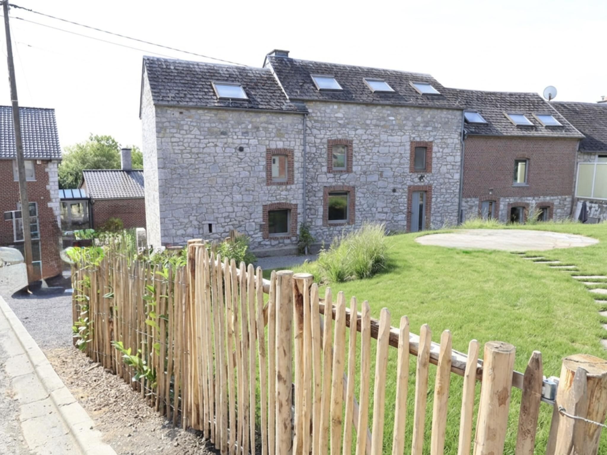 A stone building with multiple windows and a fenced yard.
