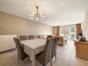A dining area with a table and chairs, a radiator, and a view of a balcony with a cityscape. - Beautiful 2-Bedroom Apartment in City Center (Blankenberge)