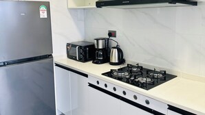 A kitchen with a stainless steel refrigerator, a microwave, a coffee maker, and a gas stove. - 14th Floor 2B with Pool, Gym & King Bed in Lavington (Nairobi)