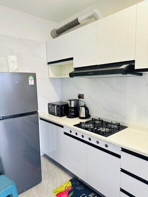 Eine Küche mit einem Edelstahl-Kühlschrank, einer Mikrowelle, einer Kaffeemaschine und einem Gasherd.