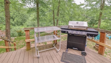 A grill on a deck with a metal cart and a vent.