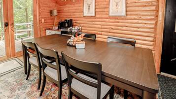 Ein Holzinterieur mit einem Esstisch, Stühlen, einer Kaffeestation und gerahmten Bildern an den Wänden.