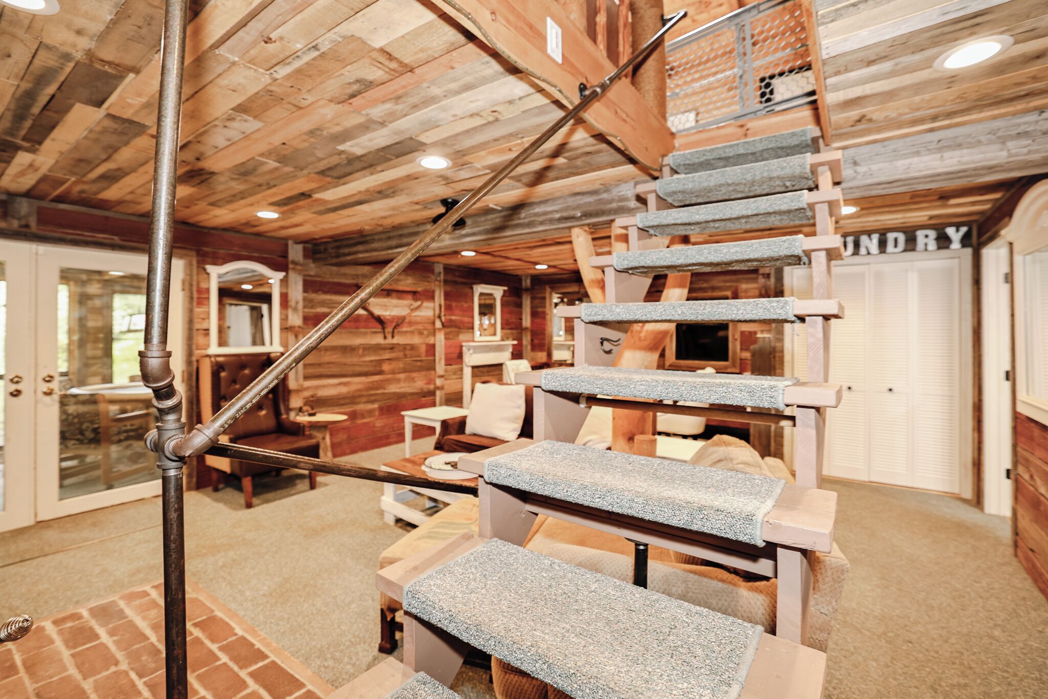 A wooden interior with a stone staircase, a laundry room, and a view of the outside.