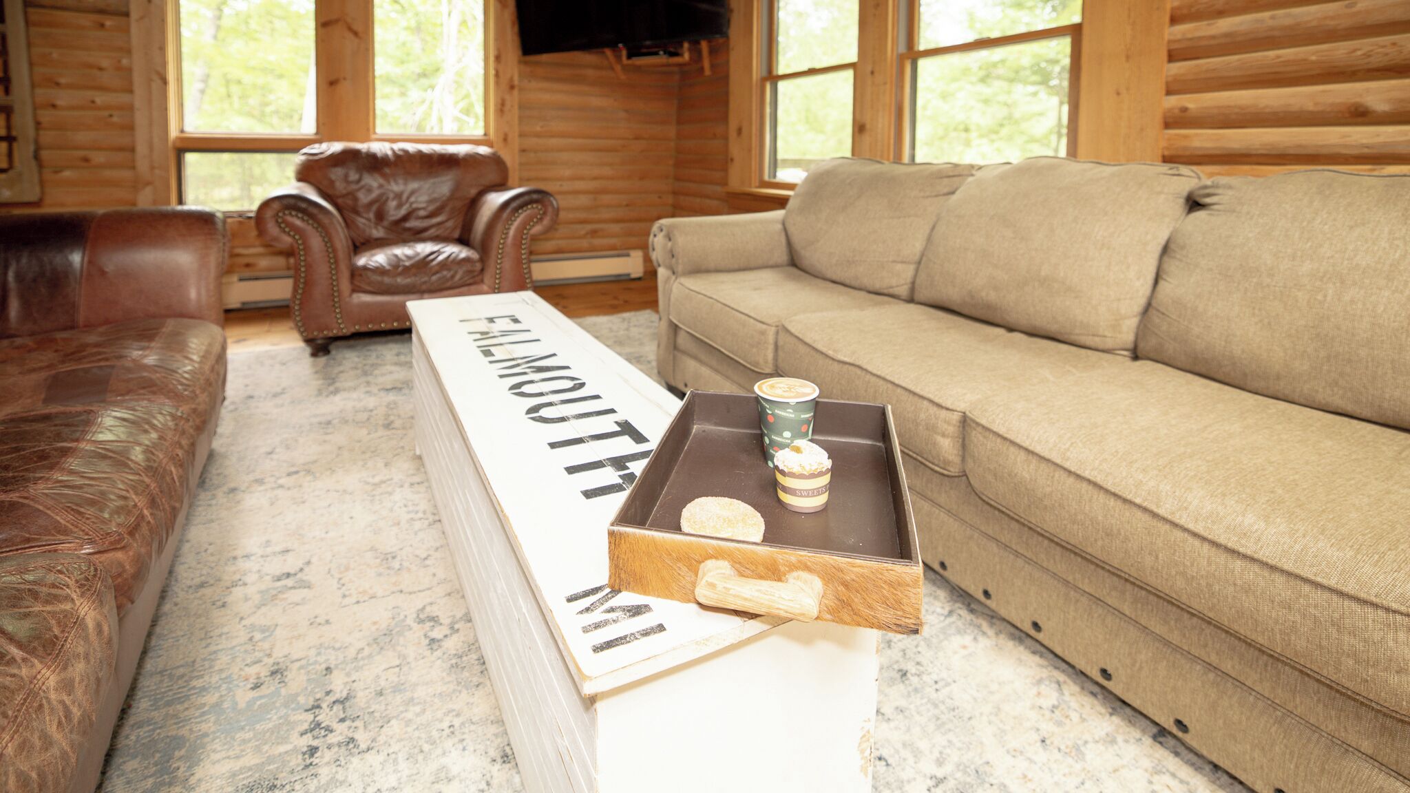 Une pièce chaleureuse avec un canapé en cuir, un divan beige et un plancher en bois.