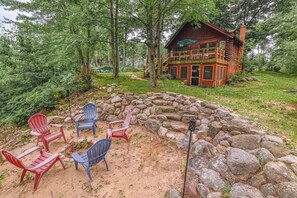 Una cabaña rústica con un hogar a piedra y sillas Adirondack.