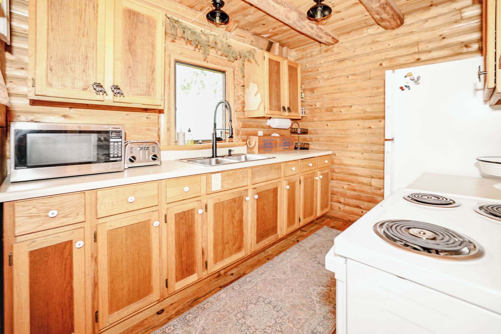 Une cuisine avec des meubles de rangement en bois, un four à micro-ondes, un grille-pain, un évier et une cuisinière.