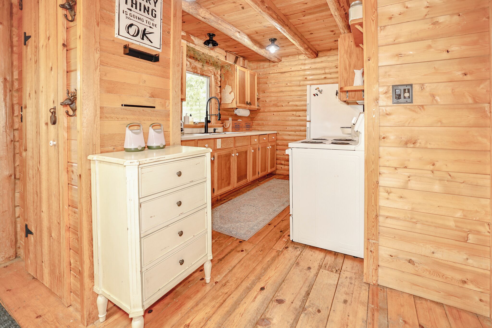 A wooden interior with a kitchen area, including a refrigerator, stove, and wooden cabinets.