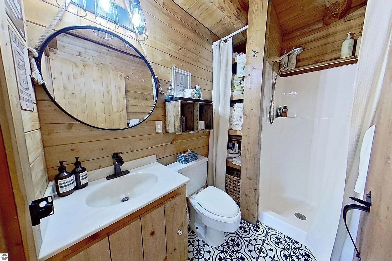 Ein Badezimmer im Holzblockhaus-Stil mit Waschbecken, Toilette und Dusche.