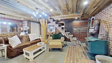 Et rustikt interiør med træloft, trappe, sofa, bord og en murstensvæg.
