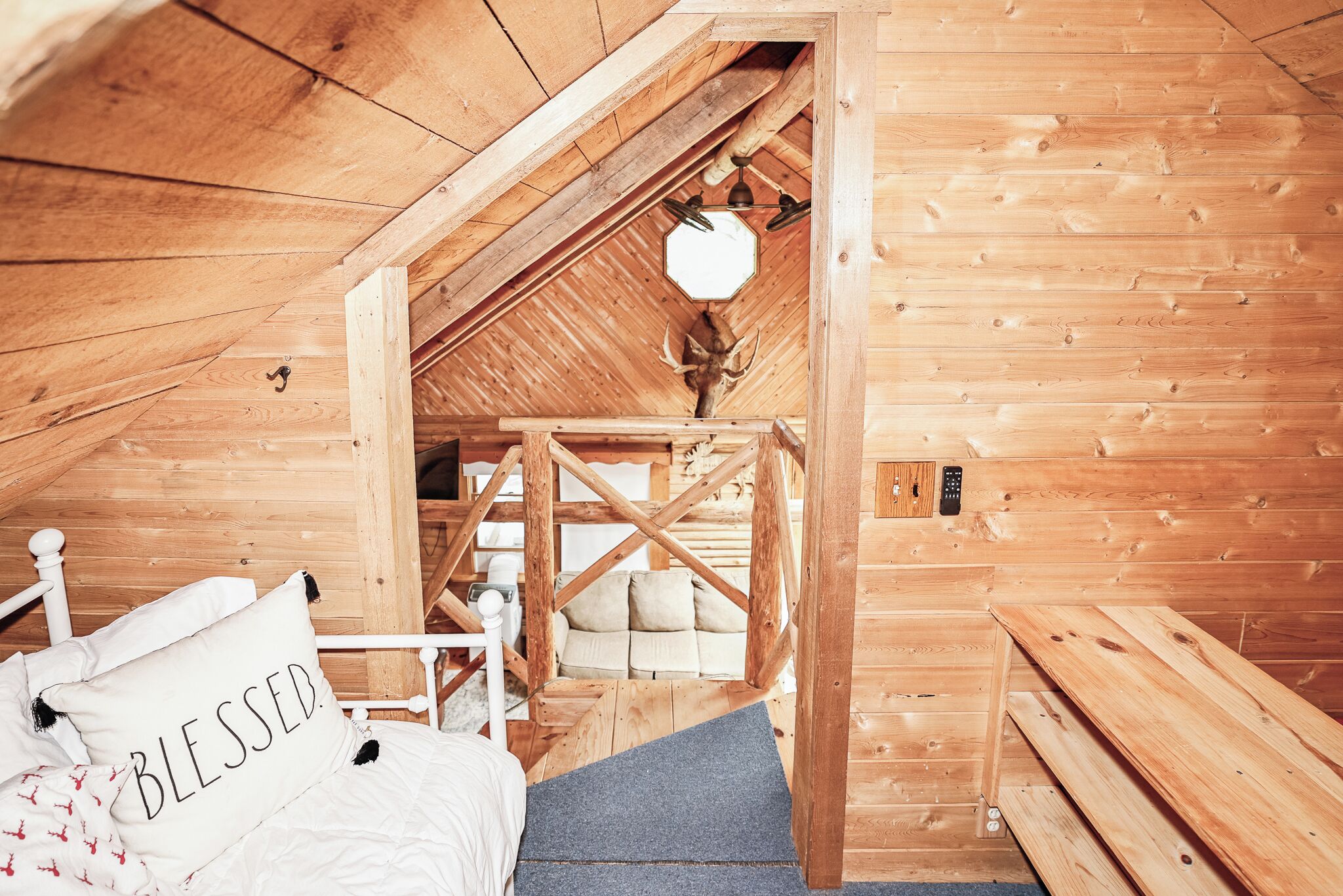 Ein Holzinnenraum mit einem Bett, einem Sofa und einer Treppe, die zu einem Dachboden führt.
