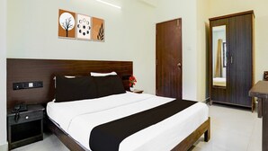 Ein Hotelzimmer mit Bett, Nachttisch, Schrank und Kleiderhocker.