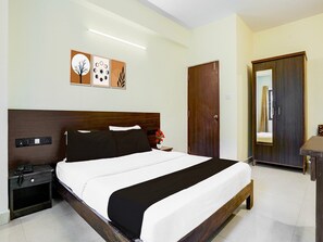 Ein Hotelzimmer mit Bett, Nachttisch, Schrank und Kleiderhocker.