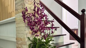 Un escalier orné d’une plante orchidée en pot et d’un ours en peluche décoratif.