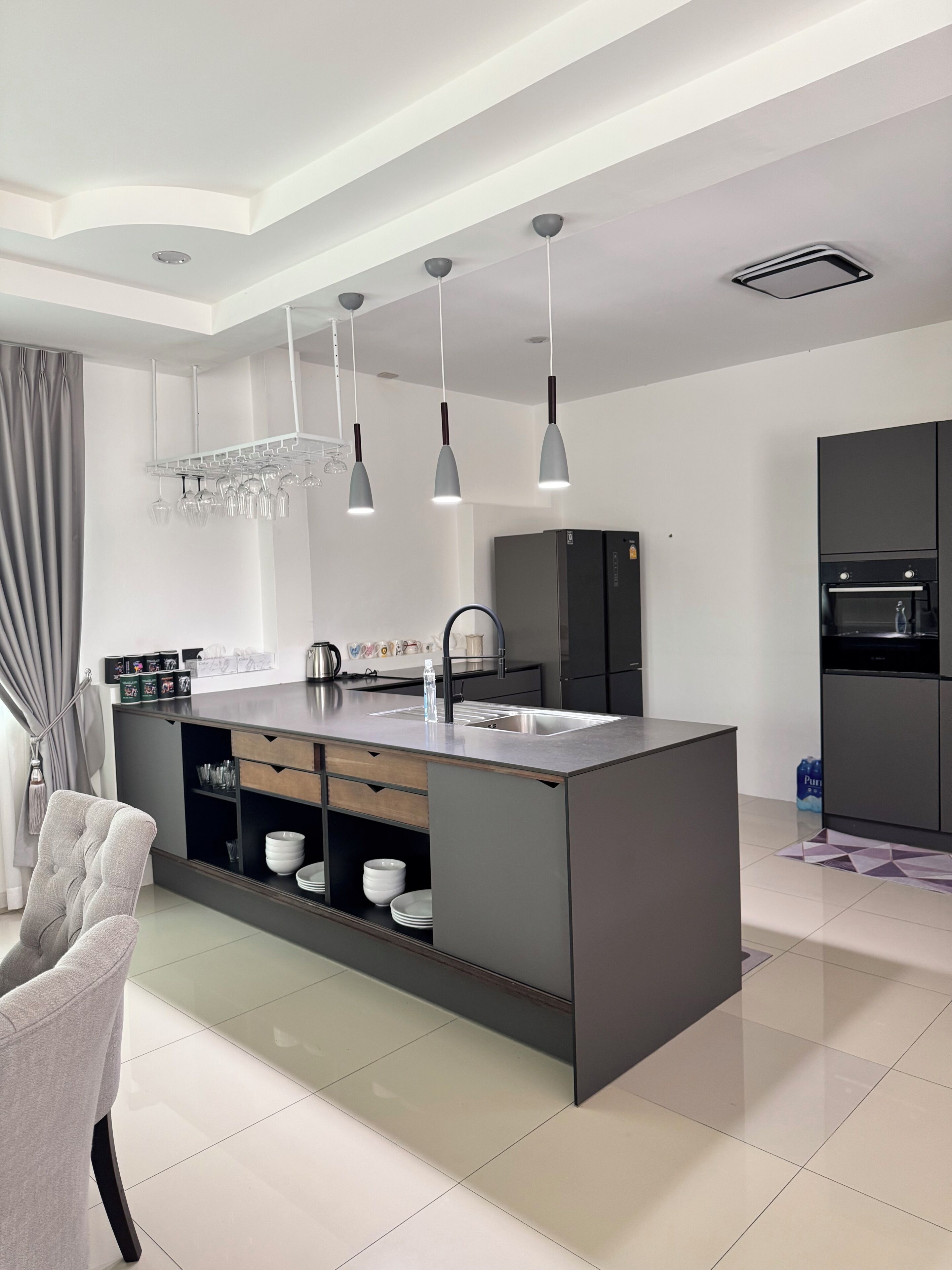 Una cocina moderna con una isla central, electrodomésticos integrados e iluminación colgante.