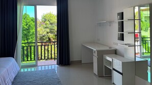 Une chambre moderne avec un lit, un bureau et un balcon donnant sur un paysage verdoyant.