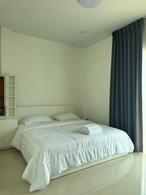 Ein Hotelzimmer mit einem Bett, einem Nachttisch, einem Regal und einem Fenster mit Vorhängen.